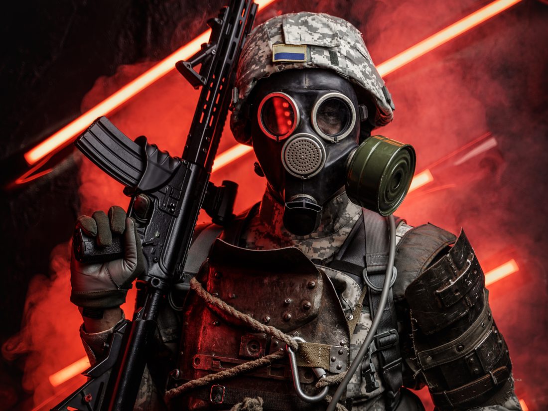 Spieler mit Gasmaske und Markierer vor rotem Licht